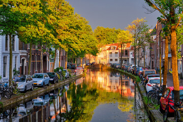 Delt canal with old houses and cars parked along on sunset