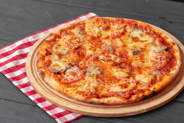 Close up of freshly baked pizza on black wooden table