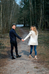 Fototapeta premium Beautiful smiling loving couple going for a walk in a forest in the spring,autumn outdoors sunny day.Rear view.