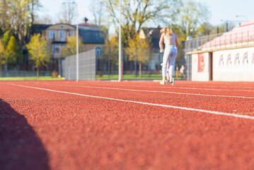 Fototapeta premium Woman with scooter on treadmill of a stadium around. Activity for weight loss and a healthy lifestyle.Selective focus.