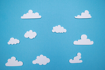 Paper cut out fluffy white clouds on a blue background/sky