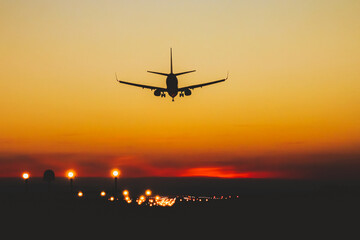Fototapeta na wymiar Airplane landing on the runway during sunset and night