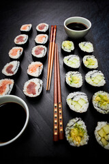 Presentation on a slate of seafood sushi and vegetable sushi with chopsticks. Oriental food