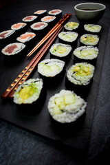 Close-up of a slate of fish sushi and vegetable sushi next to chopsticks. Oriental food
