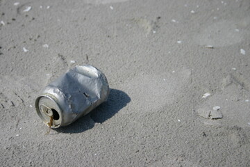 Eine leere Getränkedose aus Blech ohne Beschriftung im Sand am Strand