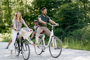 Fototapeta premium Fun family riding bicycles in the forest