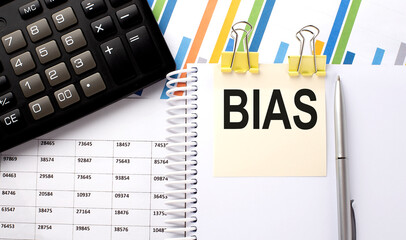 BIAS text, written on a sticker with calculator,pen on chart background.