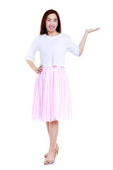Full body of smiling young Asian female in white blouse and pink skirt pointing with hand aside isolated on white background