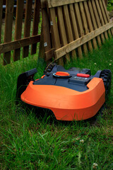 Photograph of a robotic lawn mower, working on the garden.  large lawn. copy space