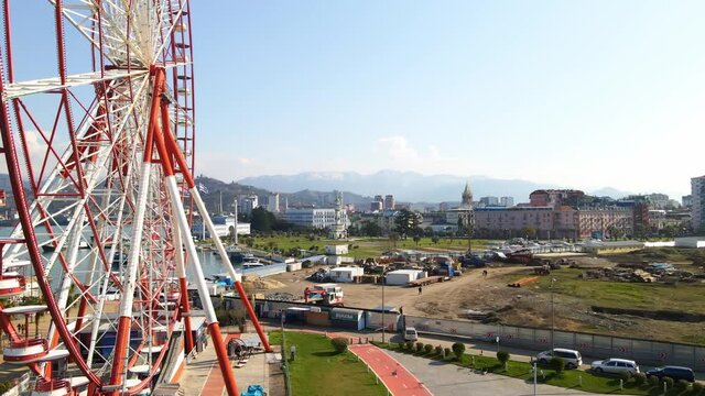 Drone footage. Aerial footage of a drone flies around a ferris wheel on the seashore.