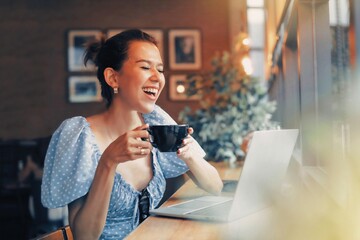 Beautiful woman drinking coffee while using laptop 