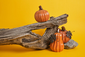 close-up of ceramic decorative halloween pumpkins on wooden timber on yellow background