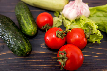 different vegetables on wooden boards. Tomatoes, cucumbers, lettuce and zucchini on a dark table.