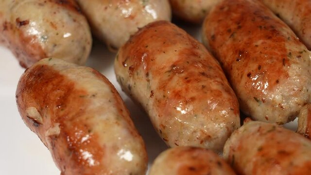 Close-up view 4k stock video footage of many hot cooked tasty pork sausages with organic spices isolated on white background spinning around slowly