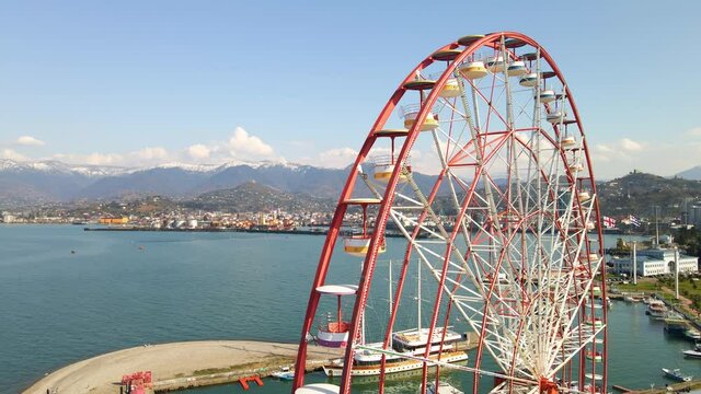 Drone footage. Aerial footage of a drone flies around a ferris wheel on the seashore.