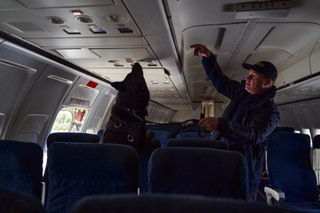 Security officer with detection dog checking passenger airplane