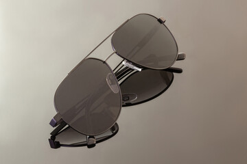 Black sunglasses on grey reflective surface, closeup. Fashion and shopping concept