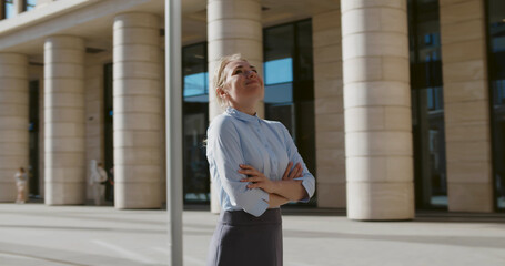 Portrait of young businesswoman with hands crossed standing outside building
