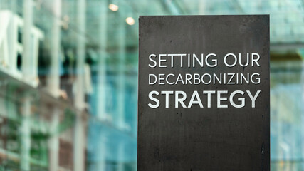 Setting our decarbonizing strategy on a city-center sign in front of a modern office building	
