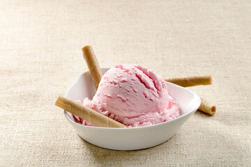 Helado de  fresa con barquillos sobre mantel beige. Strawberry ice cream with waffles on a beige...