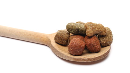 Dog food pile with wooden spoon, dry granules for pets isolated on white background