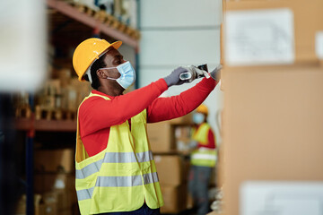 Black male worker scanning boxes in warehouse