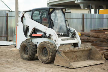 small excavator at a construction site behind a fence