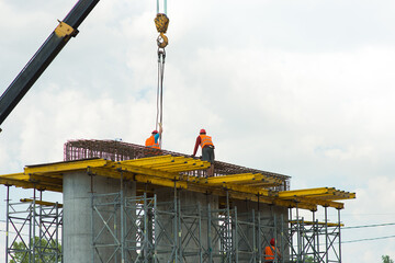 Builders remove cargo from a crane at a construction site