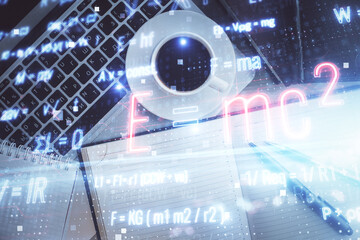 Physics and math theme hologram with formula drawings over computer on the desktop background. Top...
