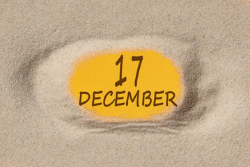 December 17. 17th day of the month, calendar date. Hole in sand. Yellow background is visible through hole. Winter month, day of the year concept