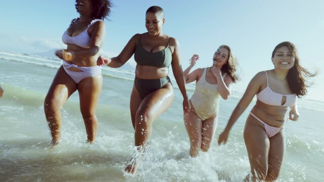 Different size women in bikinis having fun on the beach
