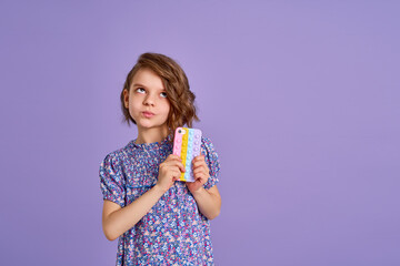 Little girl holding telephone isolated over violet color background
