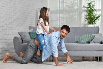 father playing with adorable little daughter in living room