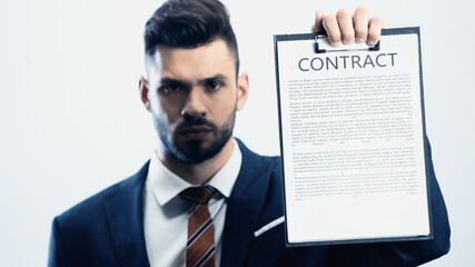 blurred businessman looking at camera while showing contract isolated on white
