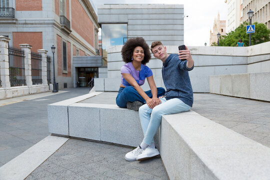 multiracial couple sitting using mobile phone to take a picture