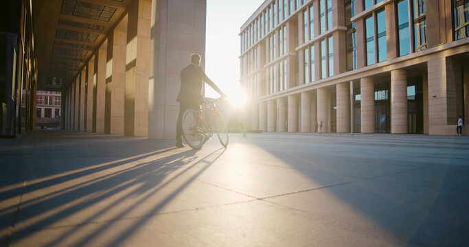 Low angle view of mature businessman in formal wear riding bicycle outside