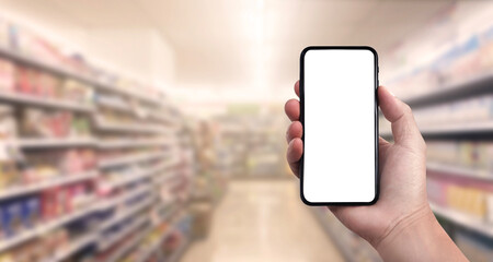 Blank screen of Mobile phone with hand holding phone on Soft blurry supermarket store background. of free space for your copy.