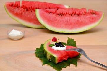 slice of watermelon with berries and original serving on the leaves