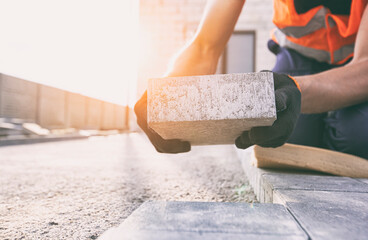 Worker lining paving slabs path