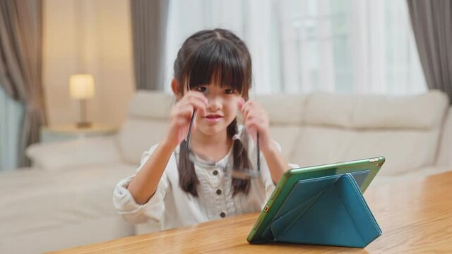 Asian young little girl wear eyeglasses after hurt eye from use tablet	