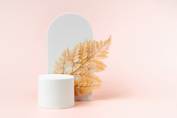 White podium with branch of leaves and arch to show cosmetic products. Beige color background for...