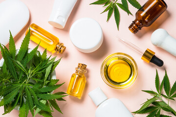 Cannabis cosmetic products. Cannabis oil, cream, soap and fresh leaves at pastel background. Flat lay.