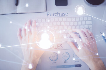 Double exposure of man's hands typing over computer keyboard and social network theme hologram drawing. Top view. People connection web concept.