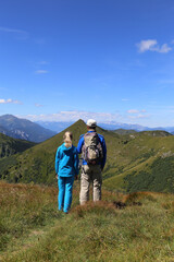 Obraz premium Zwei Wanderer genießen die schöne Aussicht in den Bergen in den steirischen Alpen. Wandern ist die beste Erholung in den Natur.