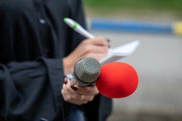 Journalist writing notes at news conference, holding microphones