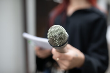 Journalist at news conference, writing notes, holding microphones