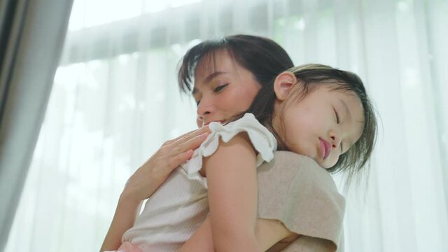 Asian loving mother hold sleeping baby girl in arm with gently at home	
