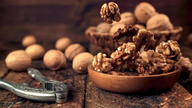 Super slow motion plate with walnuts falls on the table. On a wooden background.Filmed on a high-speed camera at 1000 fps. 