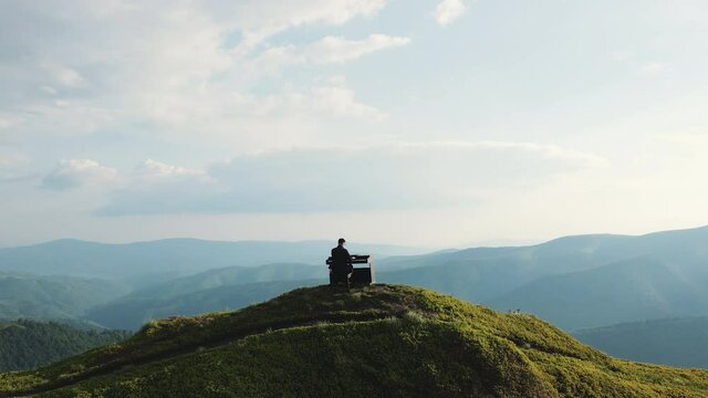 Aerial view of man two hands plays gentle classical music on a grand piano on nature. Pianist plays on grand piano in the mountains. Professional pianist. Man touches fingers on keys