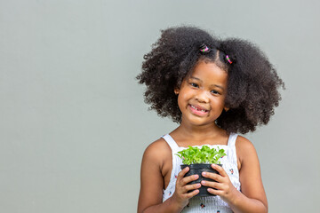 child woman afro hairstyle afro Smiling holding a plant pot showing emotionc and poses. Isolated on gray background, childhood and emotion concept.